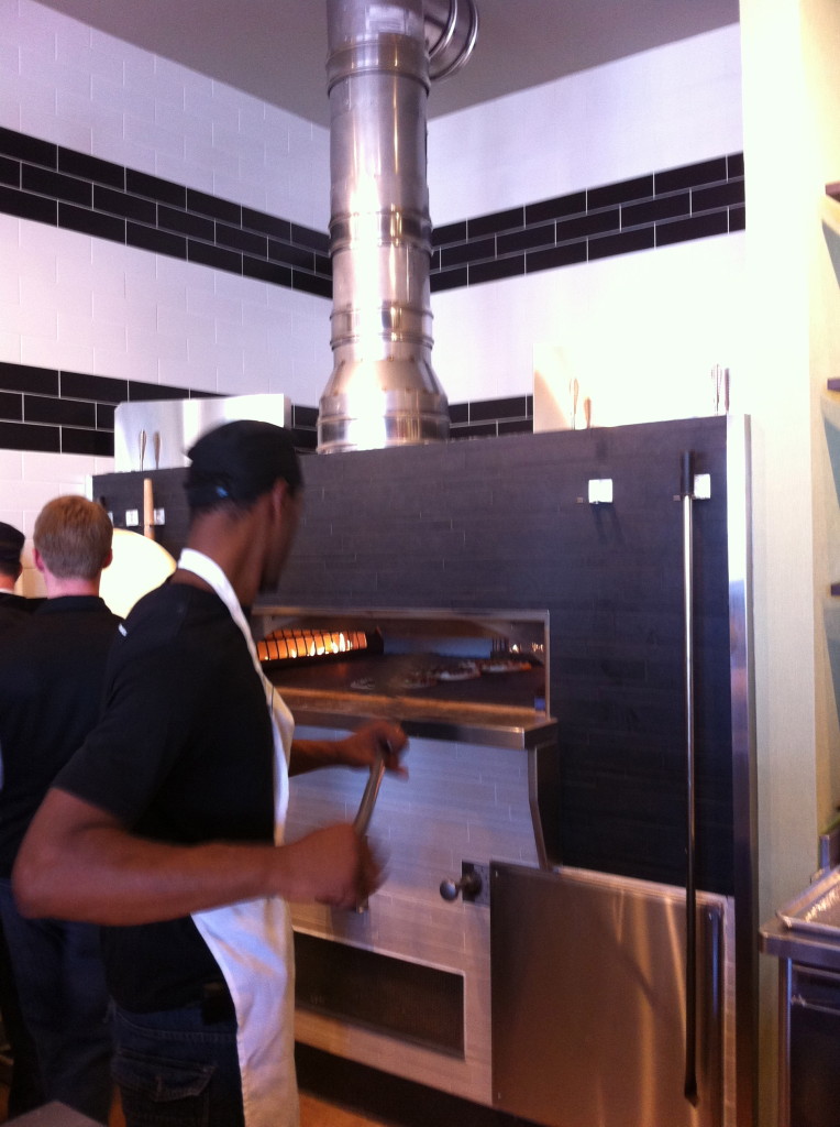 Live Basil Pizza Opens in Denver. Employee, Donyale Paige rotates pizzas in the stone slab oven.